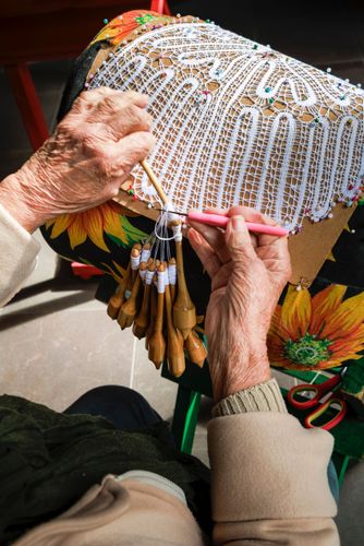 Mãos de rendeira produzindo renda de bilro 