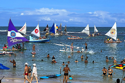 Praia do Porto de Galinhas com banhistas nas piscinas naturais e movimentação de jangadas