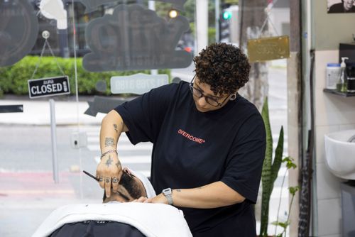 Barbeira fazendo a barba de cliente em barbearia no bairro de Perdizes 