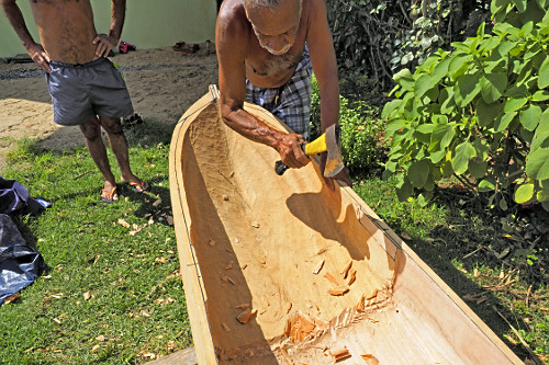Mestre canoeiro remanescente esculpindo canoa no quintal de sua moradia - Vila de Trindade - 