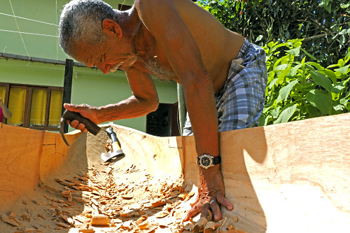 Mestre canoeiro remanescente esculpindo canoa no quintal de sua moradia - Vila de Trindade - 