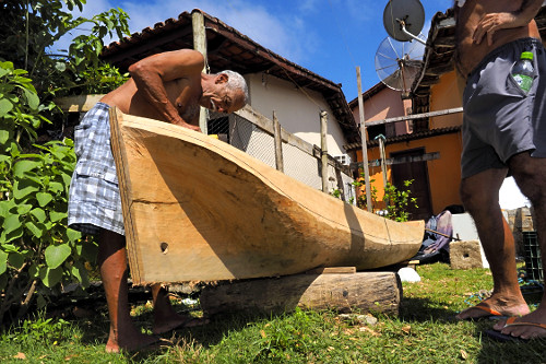 Mestre canoeiro remanescente esculpindo canoa no quintal de sua moradia - Vila de Trindade - 