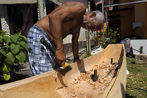 Mestre canoeiro remanescente esculpindo canoa no quintal de sua moradia - Vila de Trindade - 