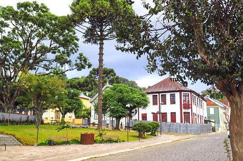 Araucaria em praça e casa com arquitetura típica italiana - ao fundo - 