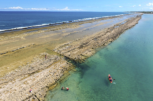 Vista de drone de passeio de caiaque próximo ao arrecife durante maré baixa na Praia de Muro Alto - Porto de