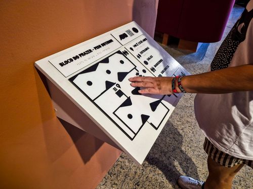 Visitante interagindo com mapa tátil do Museu de Arte Contemporânea do Ceará