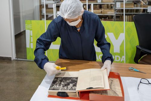 Trabalhadora do Setor de Obras Raras da Biblioteca Pública Estadual Elcy Lacerda fazendo limpeza em livro