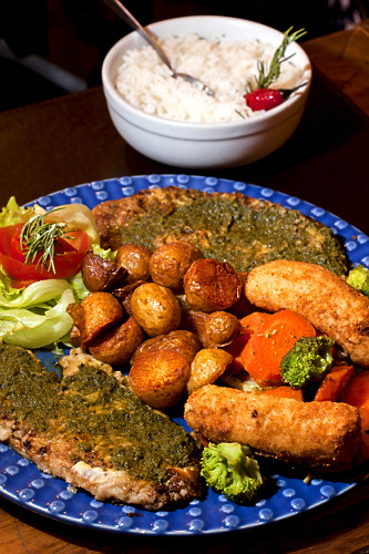 Prato com filé de tilápia ao molho pesto com batatas , legumes , salada e bananas servido em restaurante