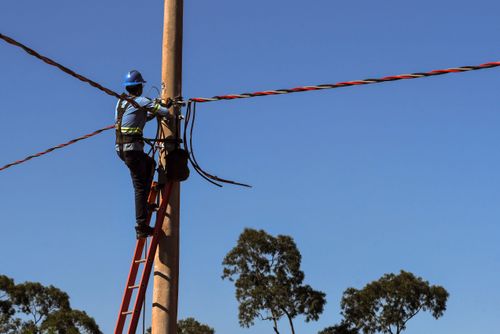 Trabalhador instalando rede elétrica em novo bairro residencial