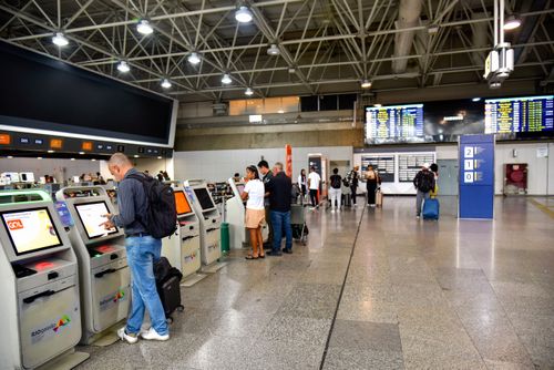 Pessoas utilizando máquinas de autoatendimento para check-in no saguão do RIOgaleão - Aeroporto Internacion