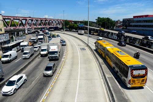 Ônibus articulado trafegando no corredor exclusivo BRT Transbrasil na Avenida Brasil - Linha Vermelha ao fund