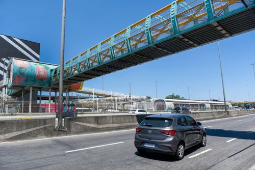 Automóvel sob a passarela para pedestres de acesso a Estação Vasco da Gama do BRT Transbrasil na Avenida Br