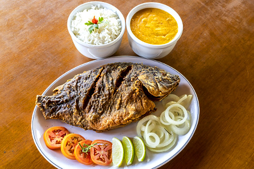 Tilápia frita servida com acompanhamentos em restaurante