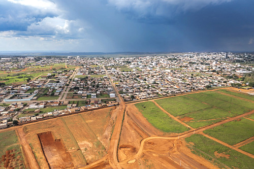 Vista de drone de loteamento e cidade ao fundo - 