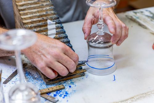 Artesão usa caneta hidrográfica na marcação do desenho de um copo de cristal para posterior lapidação de