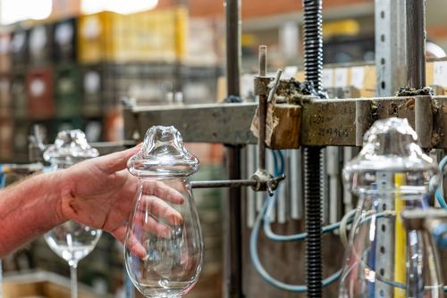 Artesão usa maçarico para corte térmico da borda do copo de cristal - fábrica de cristal