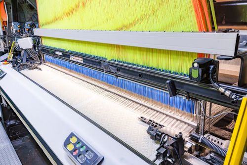 Tear industrial de indústria têxtil durante produção de tecido com desenhos em relevo