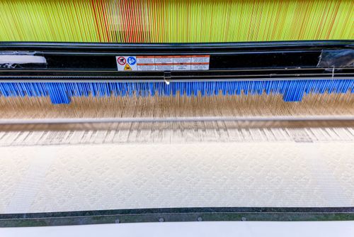 Tear industrial de indústria têxtil durante produção de tecido com desenhos em relevo
