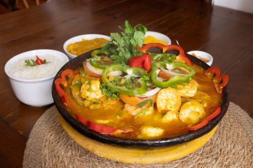 Moqueca de camarão e acompanhamentos servida em restaurante