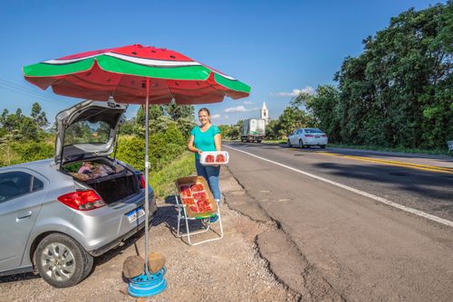 Agricultora vendendo moranguinhos produzidos em sua propriedade na margem da BR-287