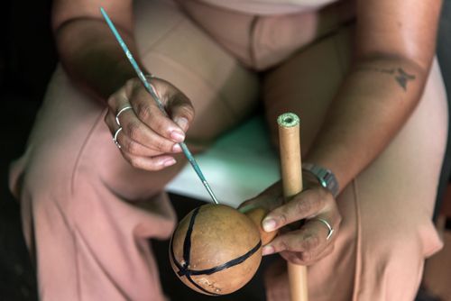 Mulher pintando cabaça na oficina de maracá durante o evento Abril Indígena 2026 na aldeia urbana multiétn