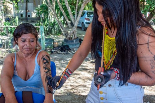 Mulheres indígenas da etnia Guarani fazendo pintura corporal na Aldeia Mata Verde Bonita ou Tekoa Ka'Aguy Ovy