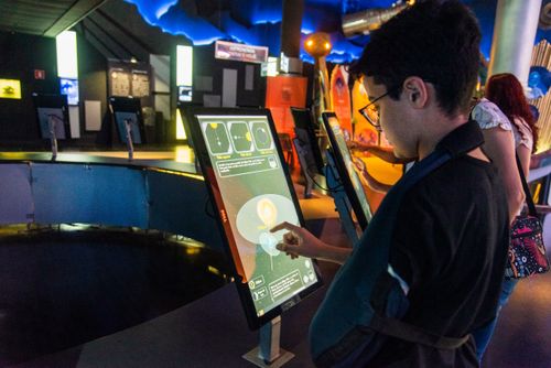Menino interagindo com painel digital no Museu do Universo no Planetário do Rio