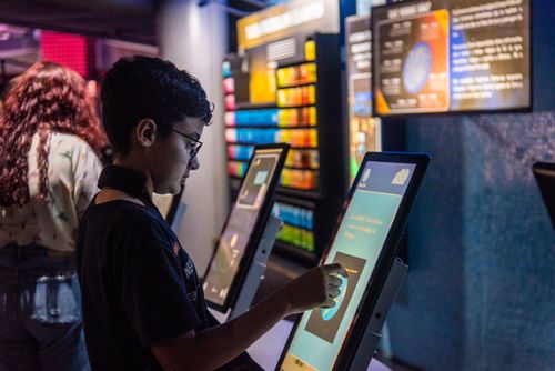 Menino interagindo com painel digital no Museu do Universo no Planetário do Rio
