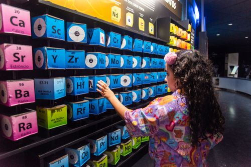 Menina interagindo com tabela periódica dos elementos no Museu do Universo no Planetário do Rio