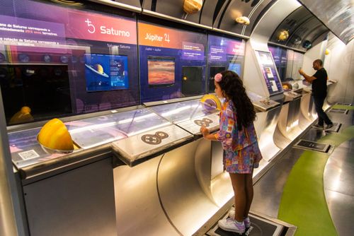 Menina observando como seu peso seria diferente no planeta Júpiter planeta no Museu do Universo no Planetári