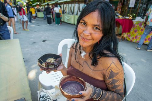 Mulher da etnia Guajajara posando com prato típico Tupi e Guajajara chamado Xibeu preparado com carne moquead