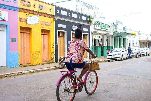 Rua de comércio e moradora pedalando bicicleta no centro da cidade