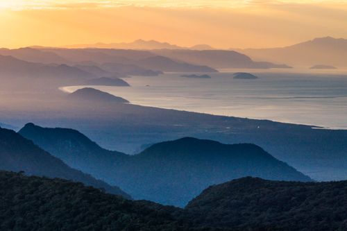 Vista de drone do litoral ao amanhecer e montanhas do Parque Estadual Serra do Mar - Núcleo Bertioga