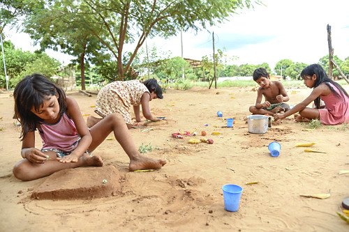Crianças indígenas da etnia Xerente brincando de fazer bolos de terra