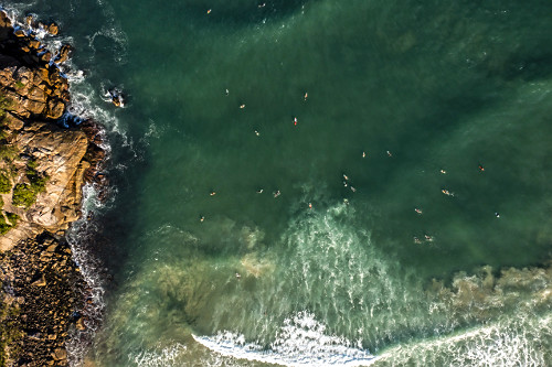 Visão perpendicular de drone de surfistas na Praia da Ferrugem