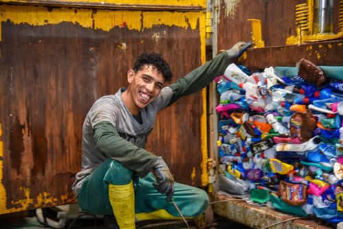 Retrato de trabalhador ao lado de prensa hidráulica em cooperativa de separação de recicláveis