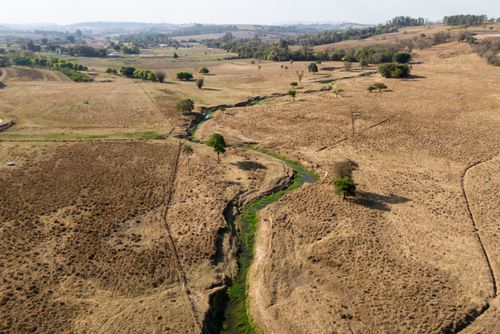 Vista de drone do Ribeirão Jacutinga afluente do rio Corumbataí e pasto seco durante estiagem