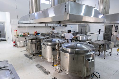Caldeirões e coifas industriais na cozinha de restaurante de preço popular 