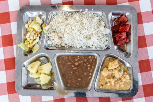 Bandeja com arroz feijão carne de frango salada de repolho batata cozida e melancia servida no restaurante de
