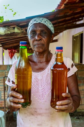 Quilombola posando com óleo extraído das sementes de coco babaçu feito artesanalmente por ela no Quilombo P